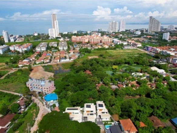 Aerial view of suburban neighborhood with modern houses, green spaces, and high-rise buildings