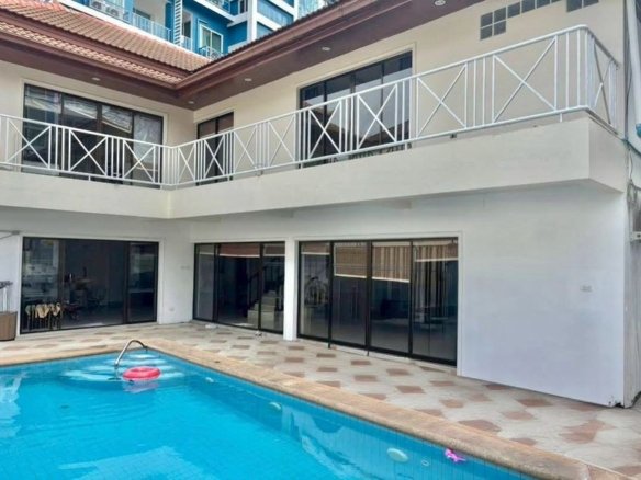 Two-story house exterior with a private swimming pool, tiled patio, and white balcony railing with X-pattern design