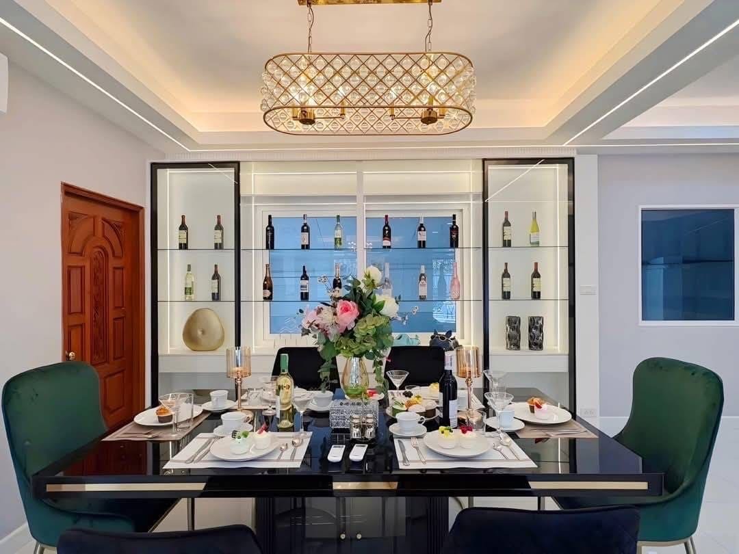 Pool Villa Central Park 4-2 (1) Elegant dining room with black table, green chairs, wine display cabinet, and floral centerpiece