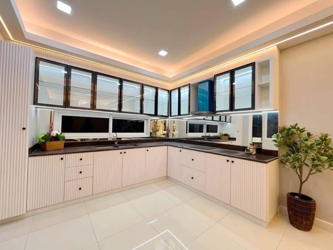 Pool Villa Central Park 4-2 (15) Modern kitchen with white cabinets, black countertops, and glass upper cabinets