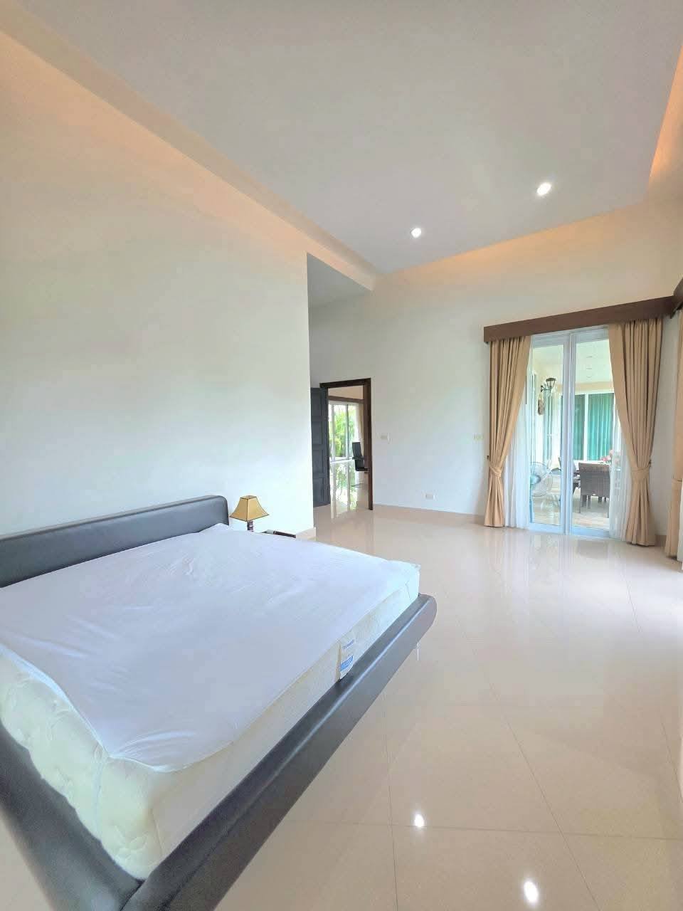 Spacious bedroom with a king-size bed, high ceilings, tiled floors, and glass doors leading to an outdoor patio