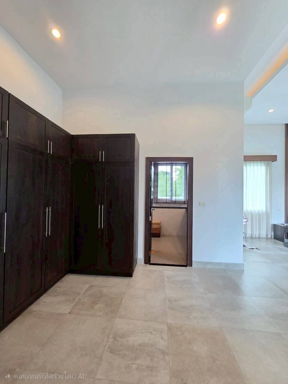 Spacious bedroom with dark wood built-in wardrobes, marble tile flooring, recessed lighting, and an open doorway leading to an adjacent room
