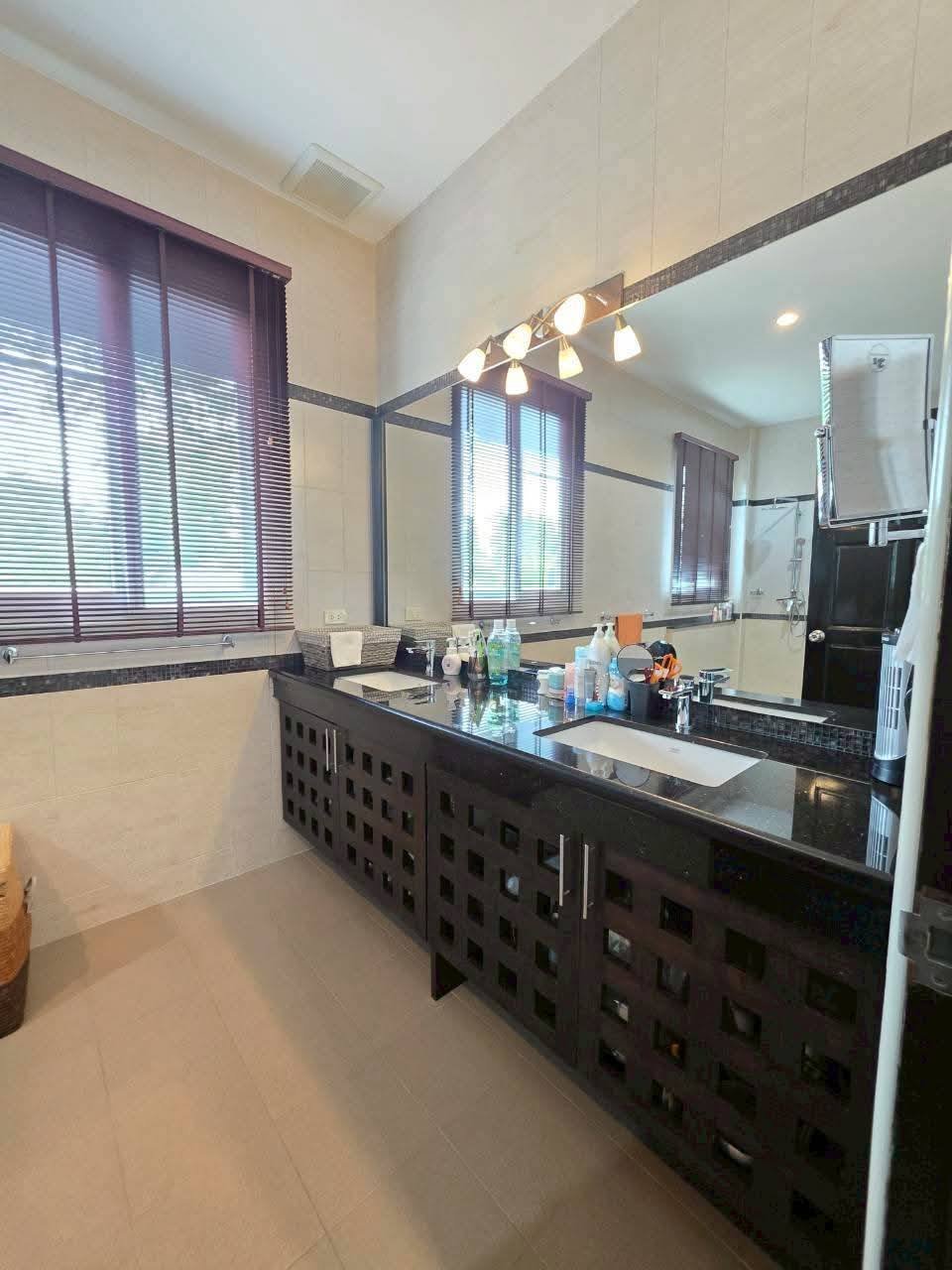 Spacious bathroom with a dark wood double vanity, black granite countertop, large mirror, and a glass-enclosed shower in the background