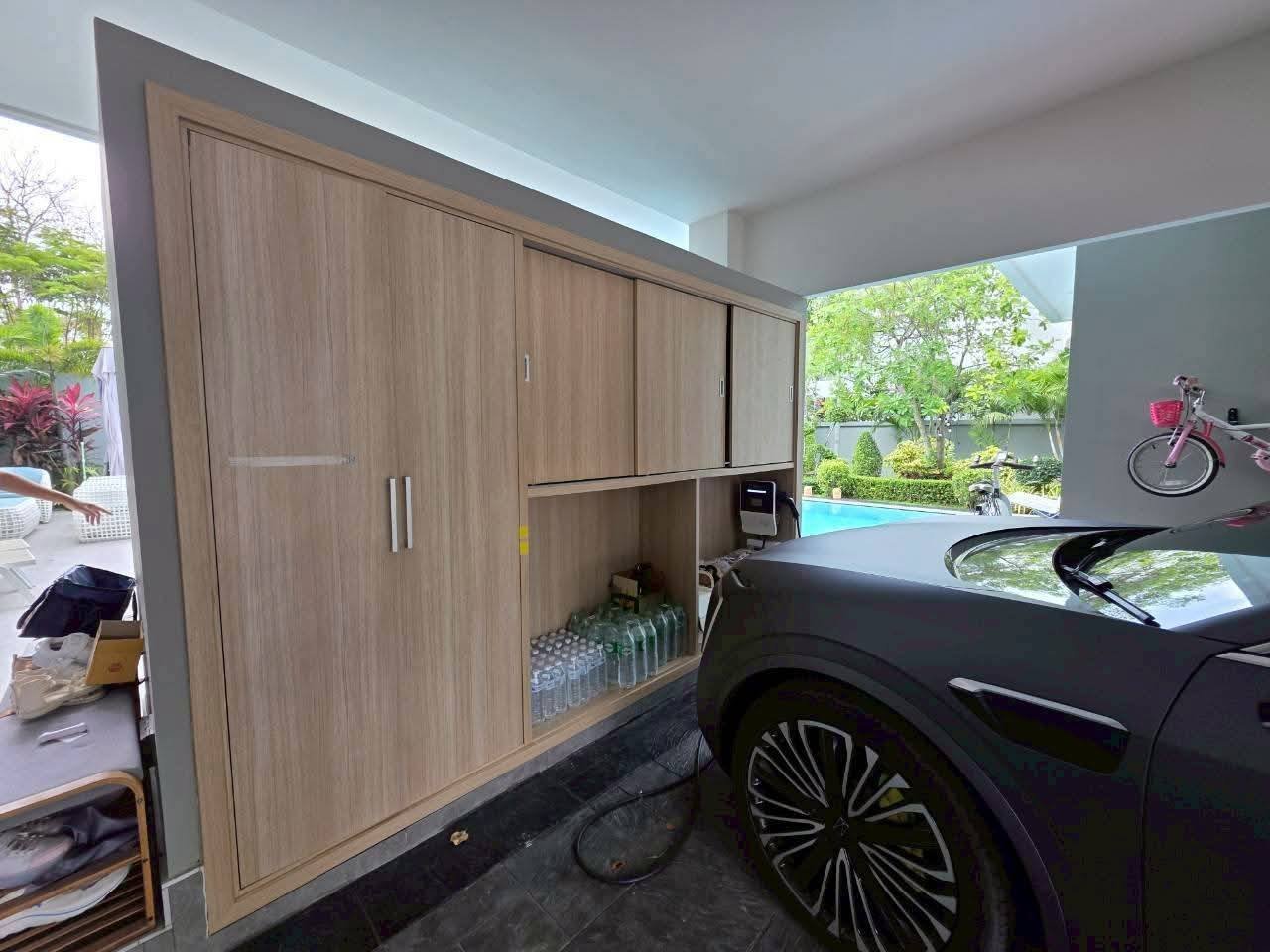 Modern garage interior with wooden storage cabinets and black car parked