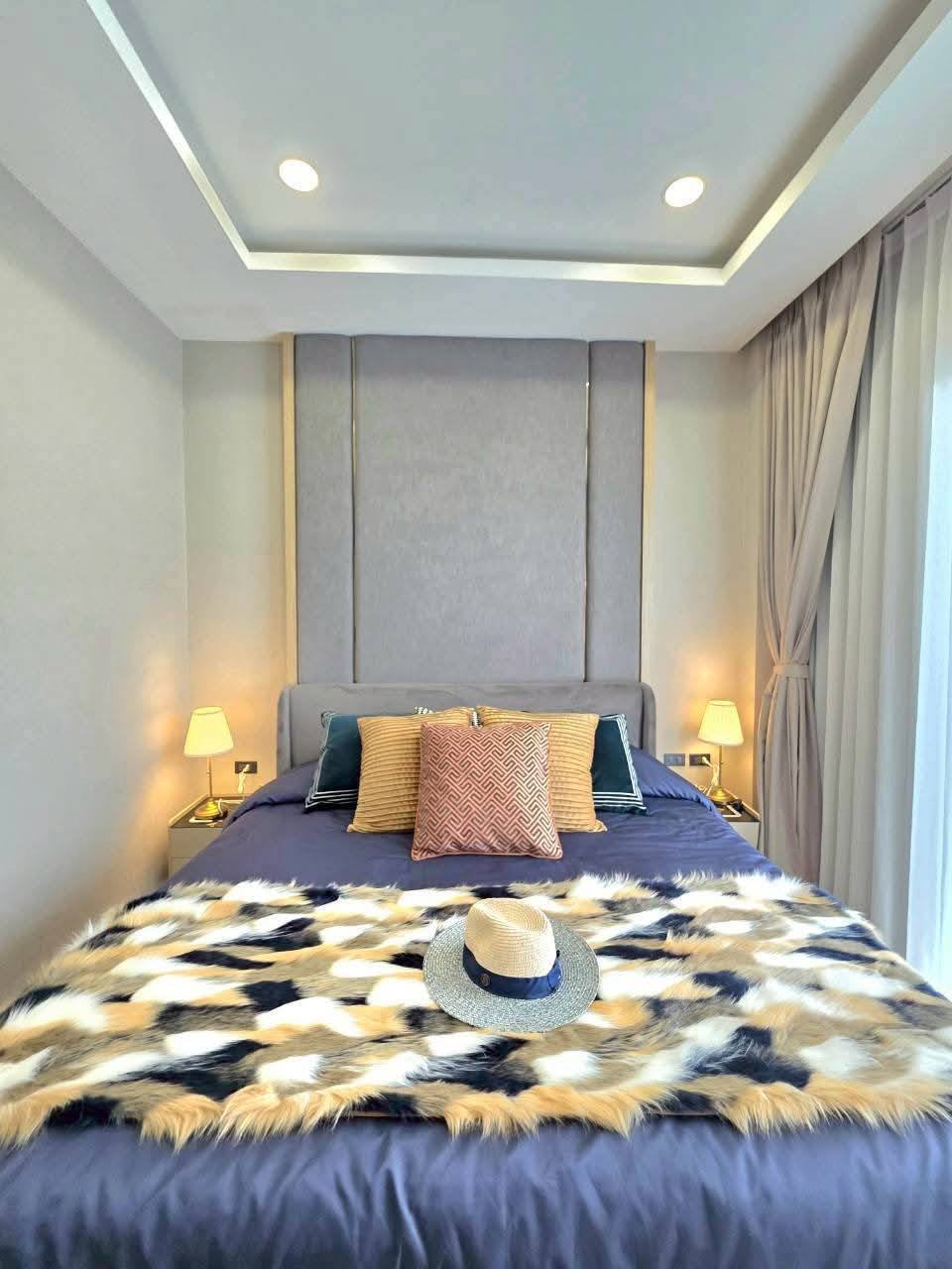 Modern bedroom with gray upholstered headboard and blue bedding, recessed ceiling lighting