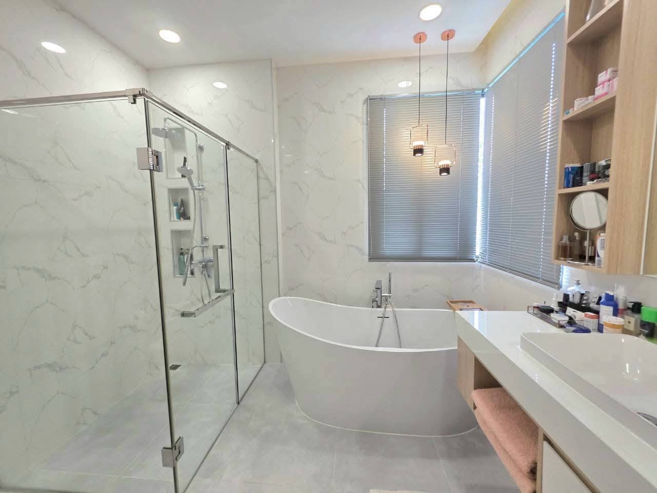 Modern luxury bathroom with marble walls, freestanding tub, glass shower enclosure