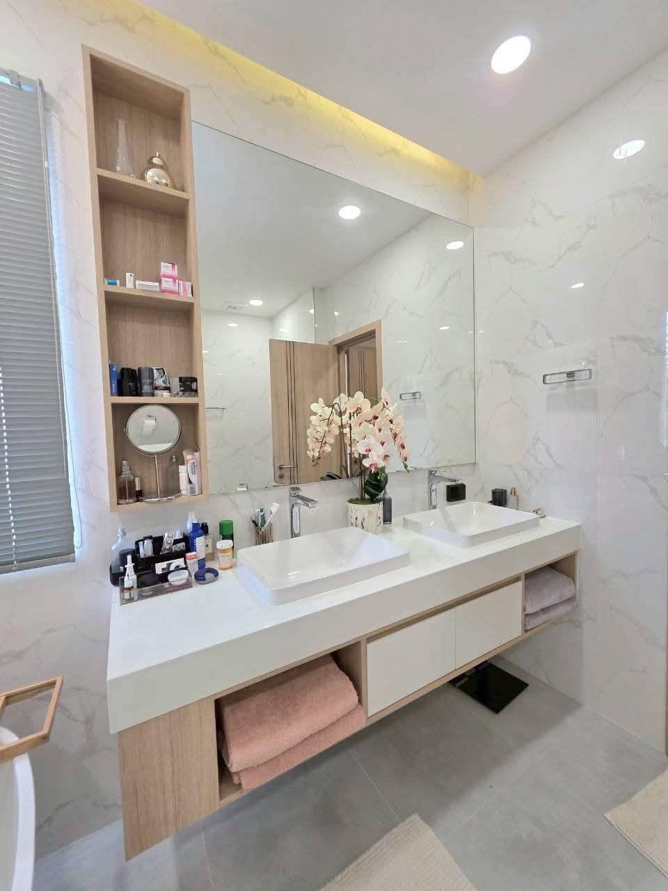 Modern luxury bathroom with dual sinks, marble walls, wooden vanity storage