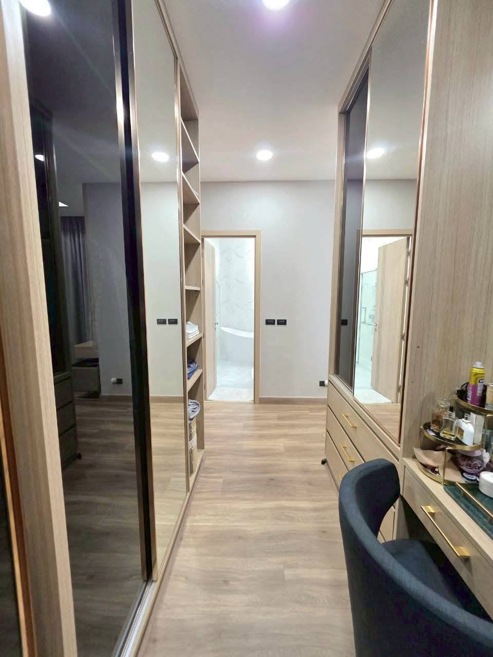 Modern walk-in closet with mirrored doors, wood flooring, and built-in shelving