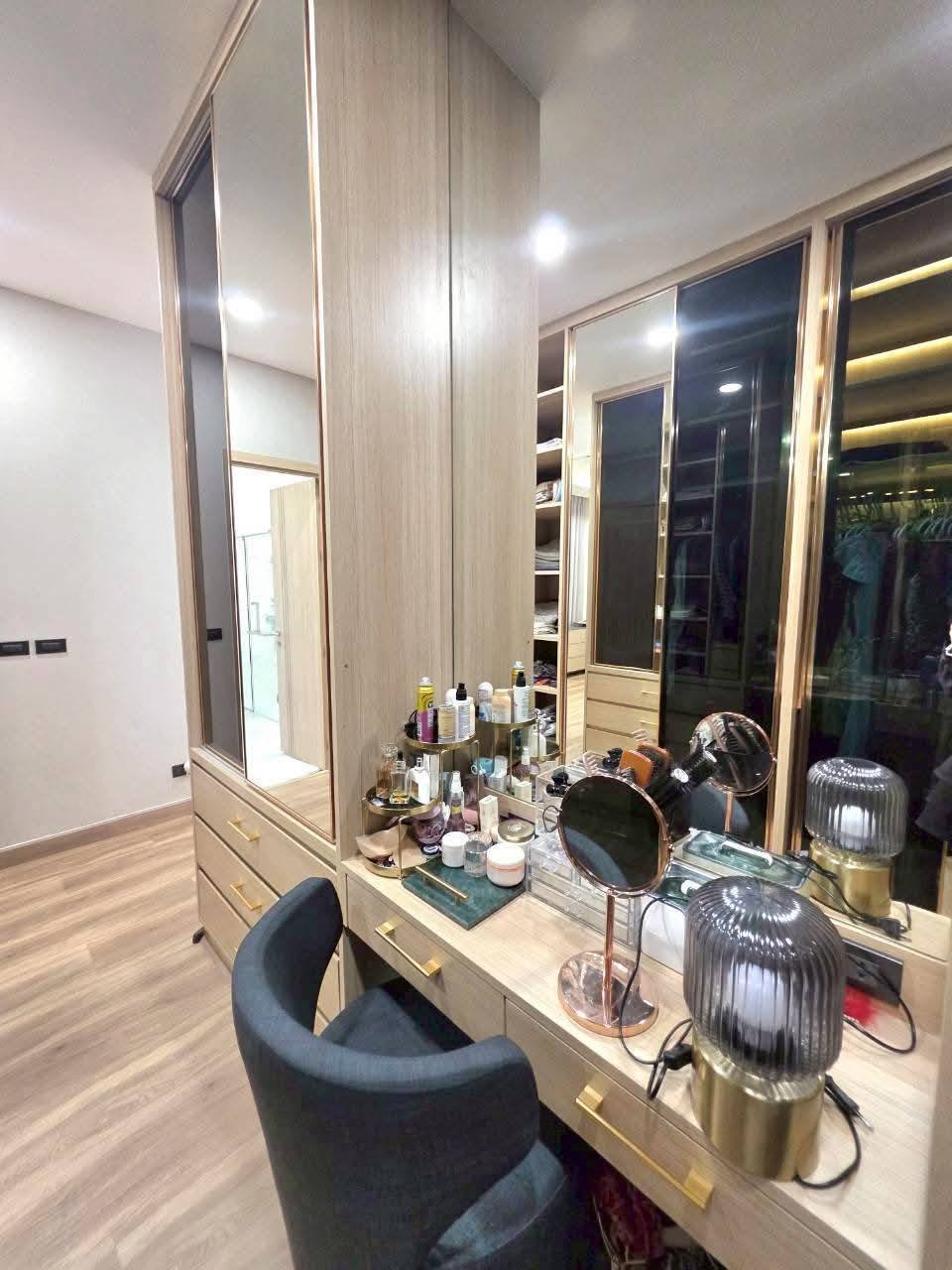 Modern luxury walk-in closet with vanity mirror, lighting, and storage cabinets