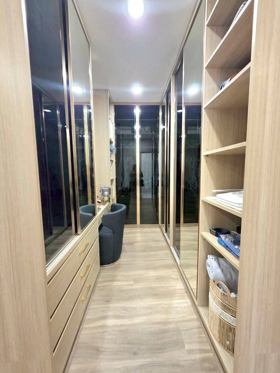 Modern walk-in closet with mirrored doors, wooden shelving, and recessed lighting