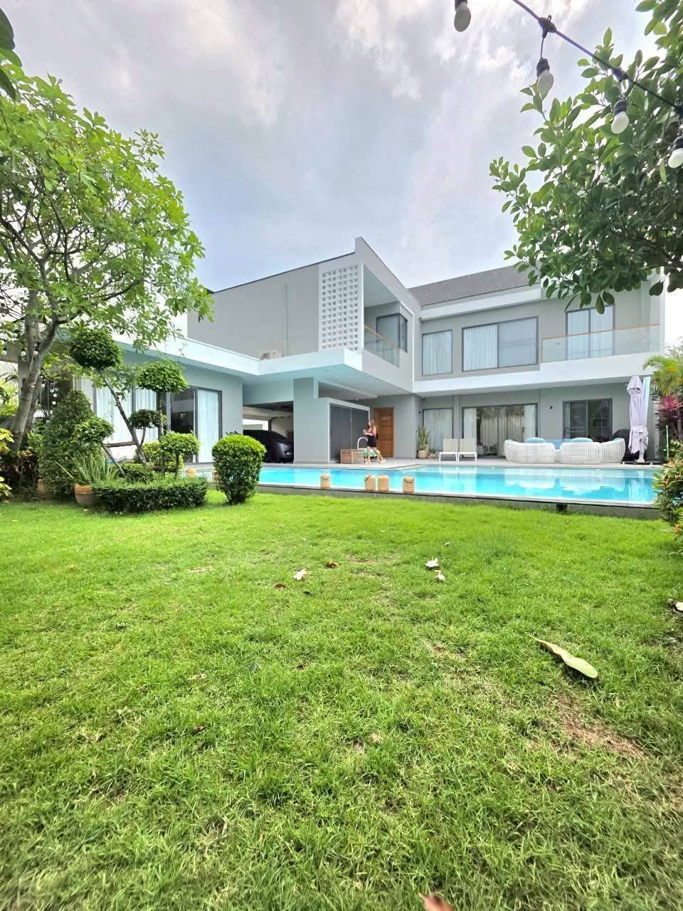 Modern two-story white house with swimming pool and manicured lawn
