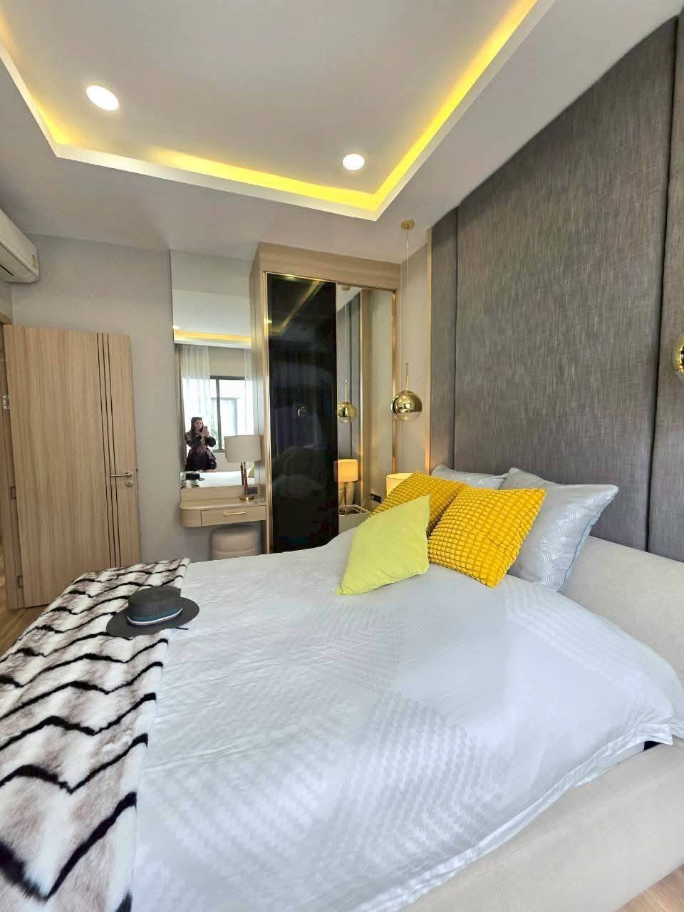 Modern bedroom with gray headboard, yellow pillows, and ambient ceiling lighting