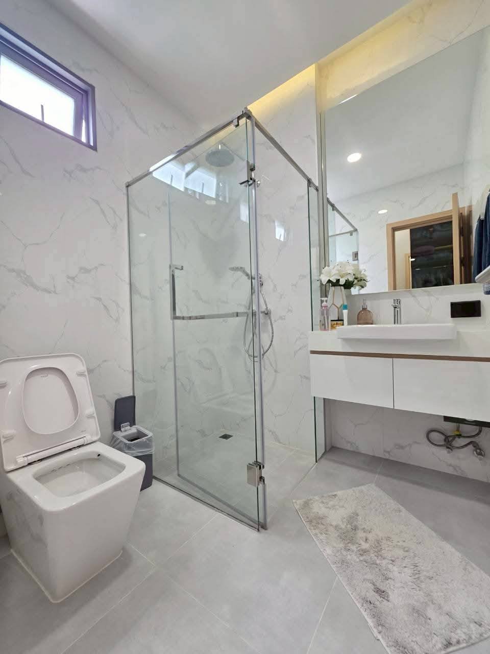 Modern luxury bathroom with marble tiles, glass shower enclosure, white vanity
