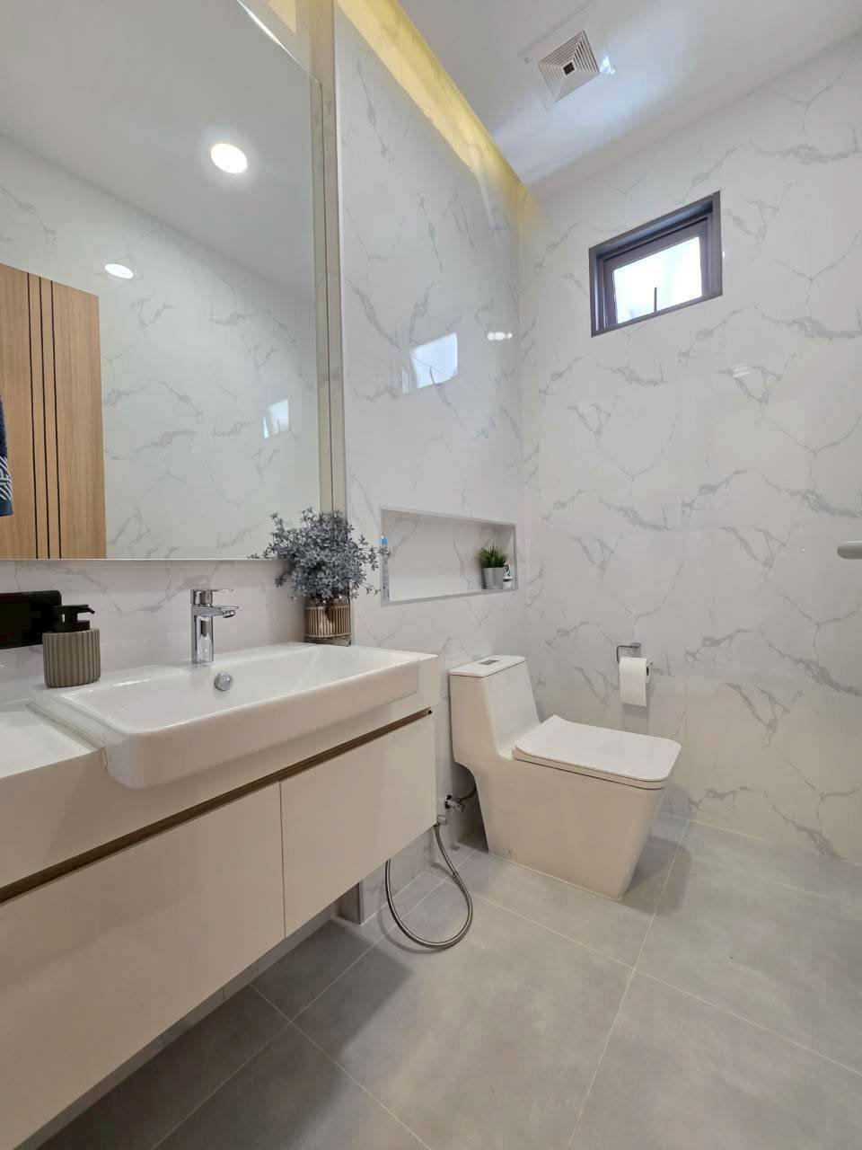 Modern bathroom with marble walls, white vanity, and toilet fixture