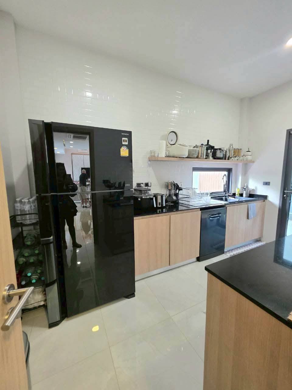 Modern kitchen with black appliances, light wood cabinets, black countertops