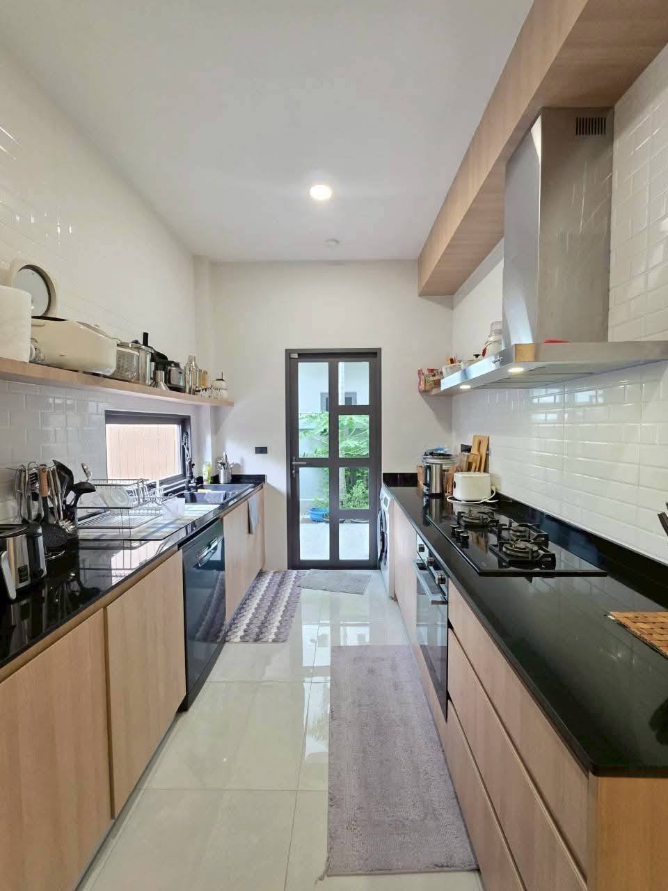 Modern galley kitchen with wood cabinets, black countertops, white subway tile backsplash