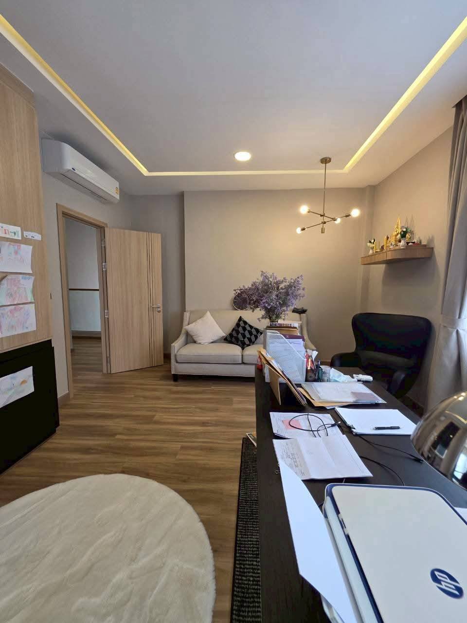 Modern office space with desk, sofa, wooden flooring, and ambient ceiling lighting