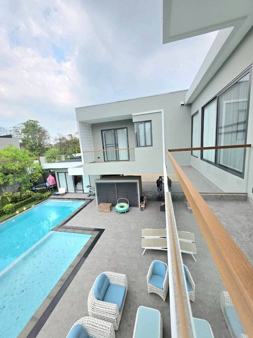 Modern two-story white house with swimming pool and outdoor patio furniture