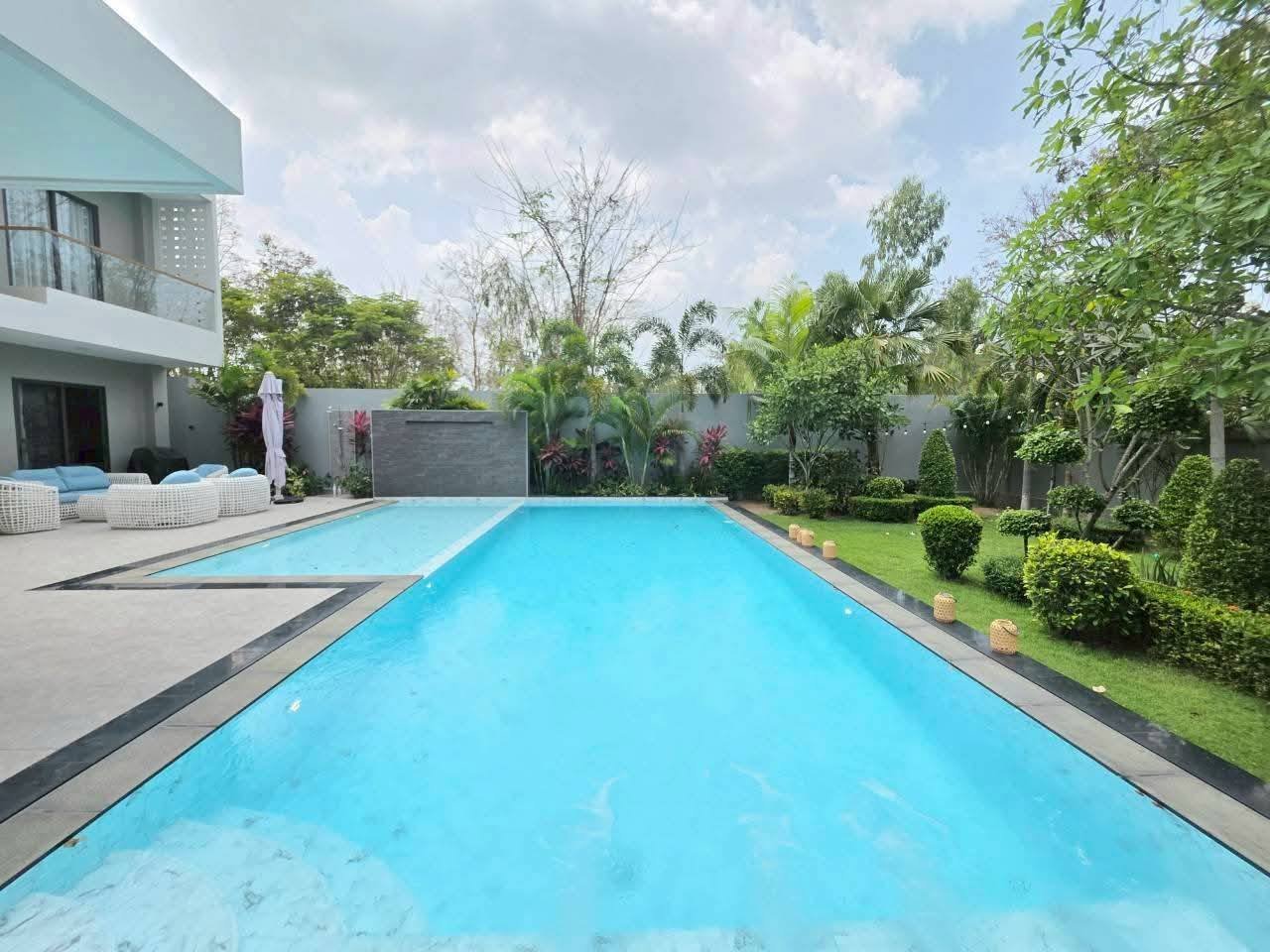 Modern turquoise swimming pool with landscaped garden and contemporary house architecture