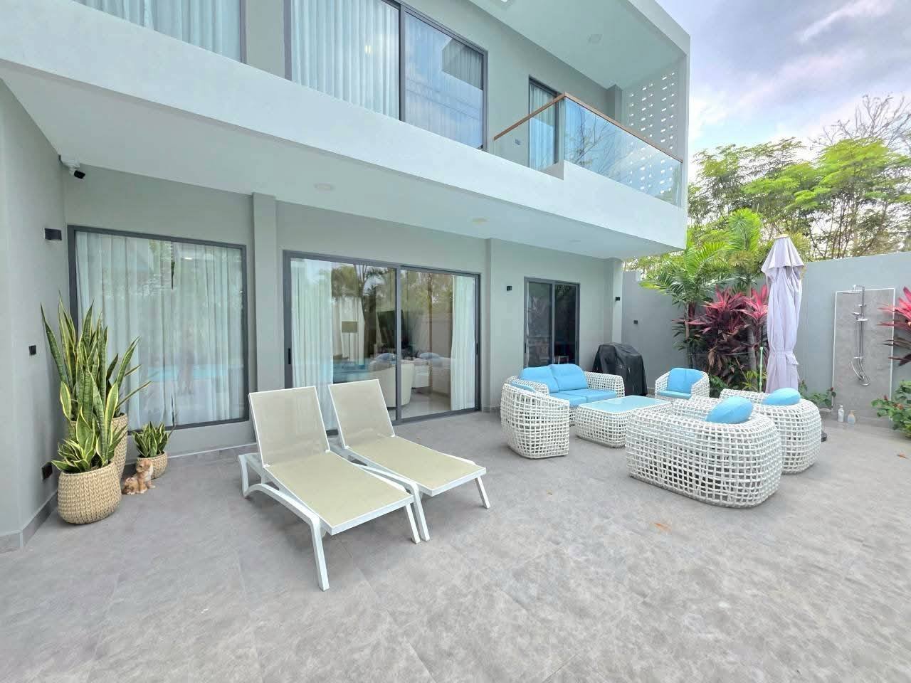 Modern white villa with patio furniture and tropical plants courtyard