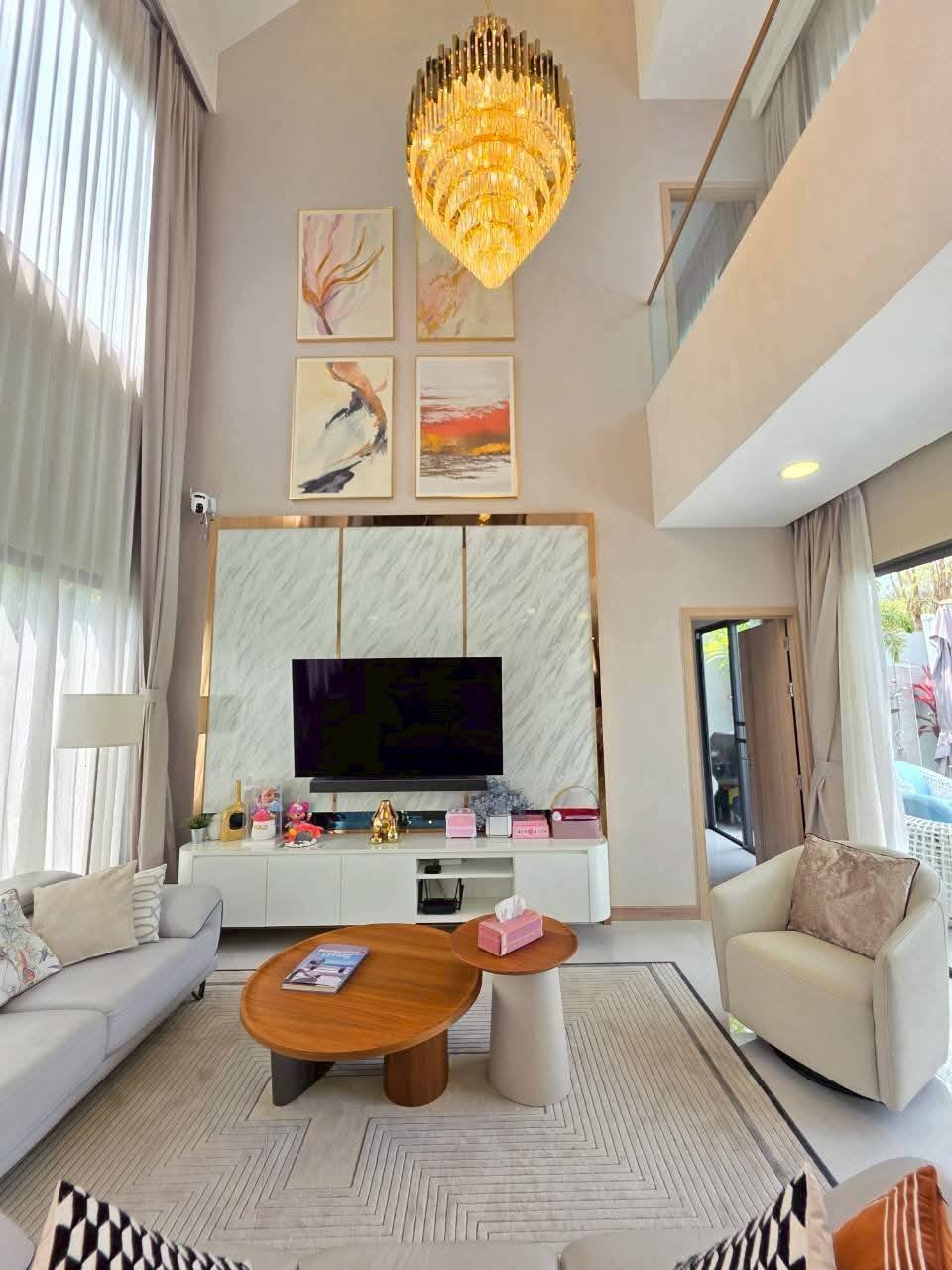 Modern luxury living room with marble fireplace, chandelier, and high ceilings