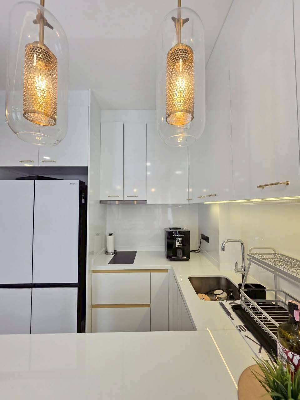Modern kitchen with white cabinetry, pendant lights, stainless steel sink